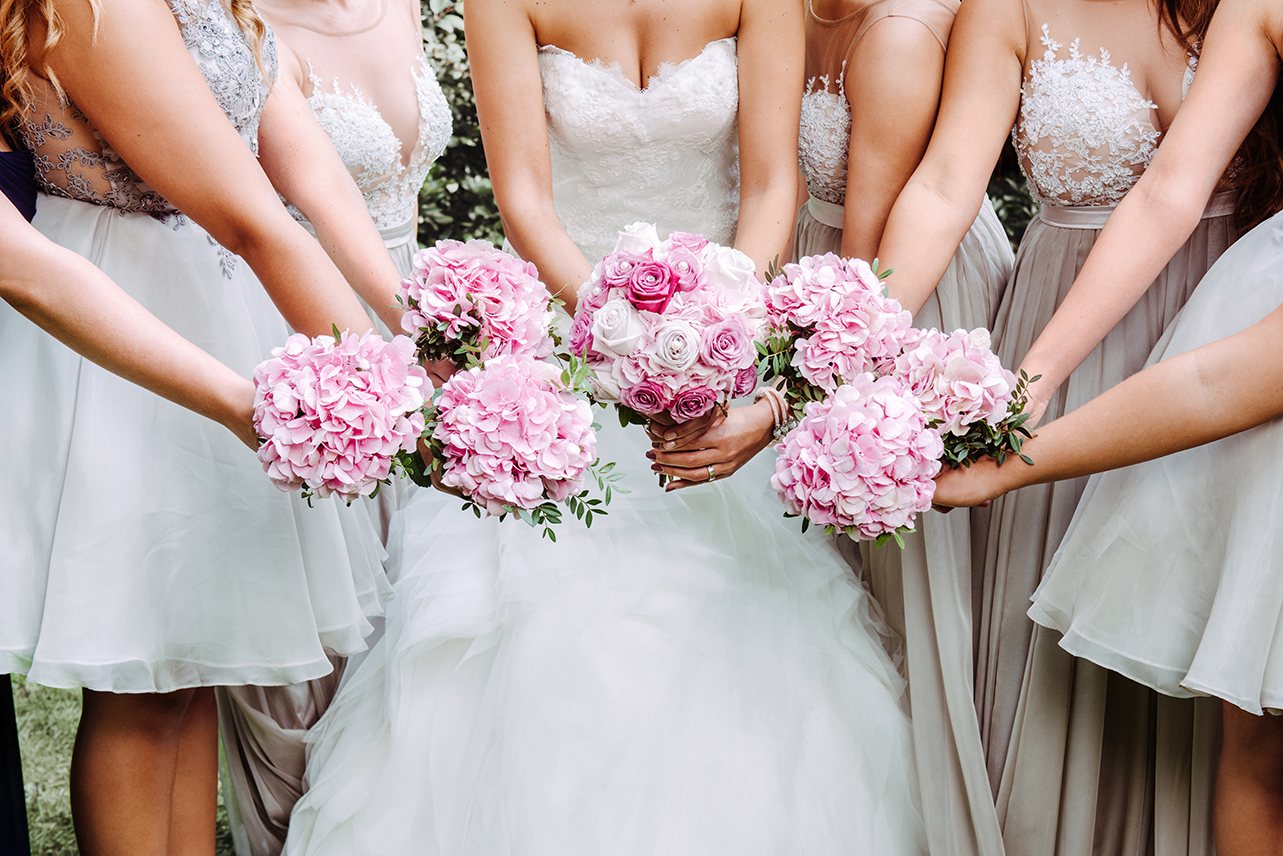 Detailaufnahme von Jeean Hochzeitsfotografie – Die Trauzeuginnen und die Braut halten ihre Blumen nach vorne, eingefangen in einem emotionalen Moment, der die Stimmung des Tages widerspiegelt.