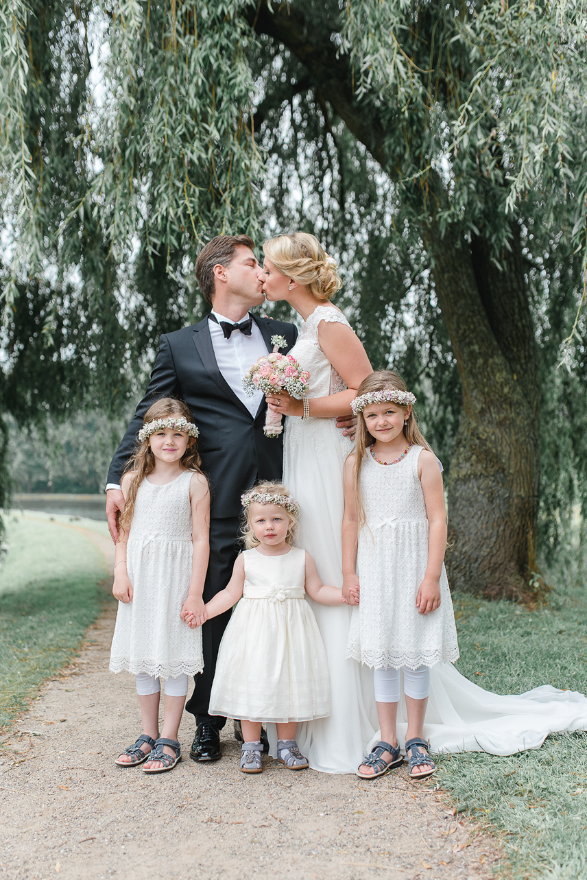 Catherina und Matthias mit drei Kindern vor sich, eingefangen in einem liebevollen Moment in der Natur.