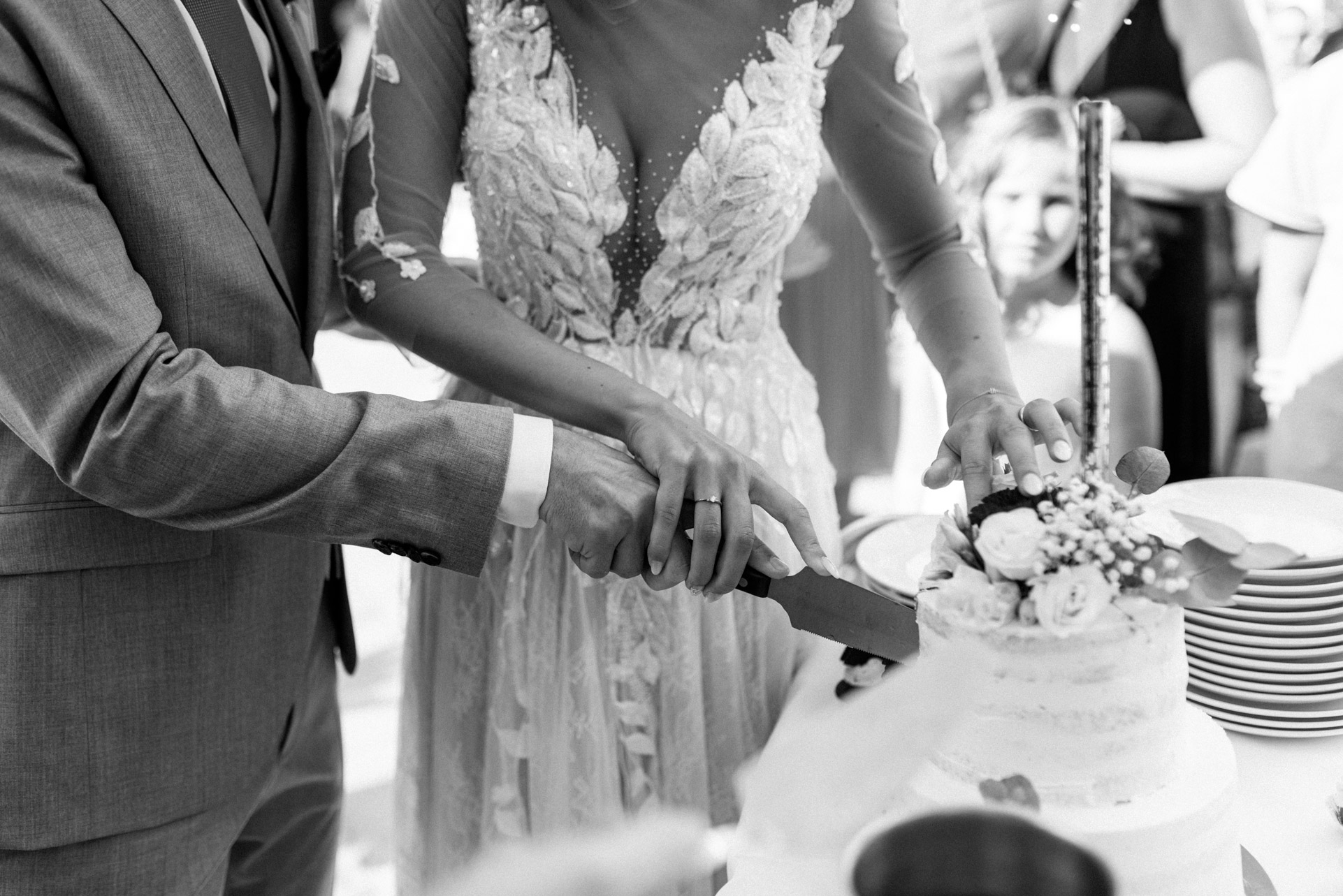 Braut und Bräutigam schneiden gemeinsam die Hochzeitstorte an, Nahaufnahme ihrer Hände und der Torte
